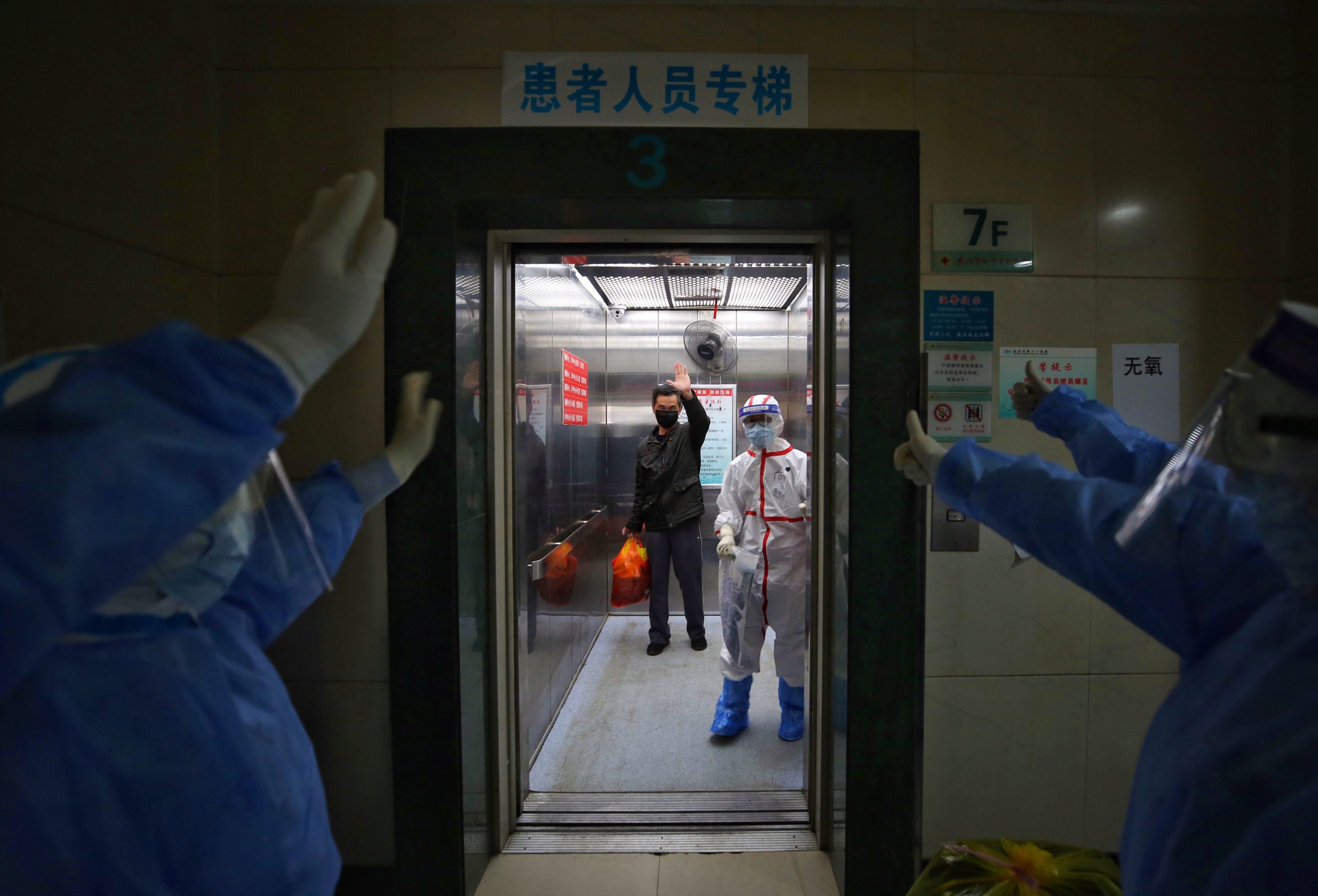 caption: Medical staff wave goodbye to a recovered COVID-19 coronavirus patient at the Red Cross Hospital in Wuhan in China's central Hubei province on March 16, 2020. (STR/AFP via Getty Images)