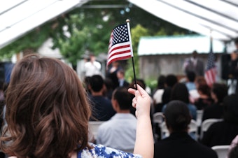 caption: A child holds a U.S. flag at a naturalization ceremony at the Wyckoff House Museum in Brooklyn, on June 14, in New York City.