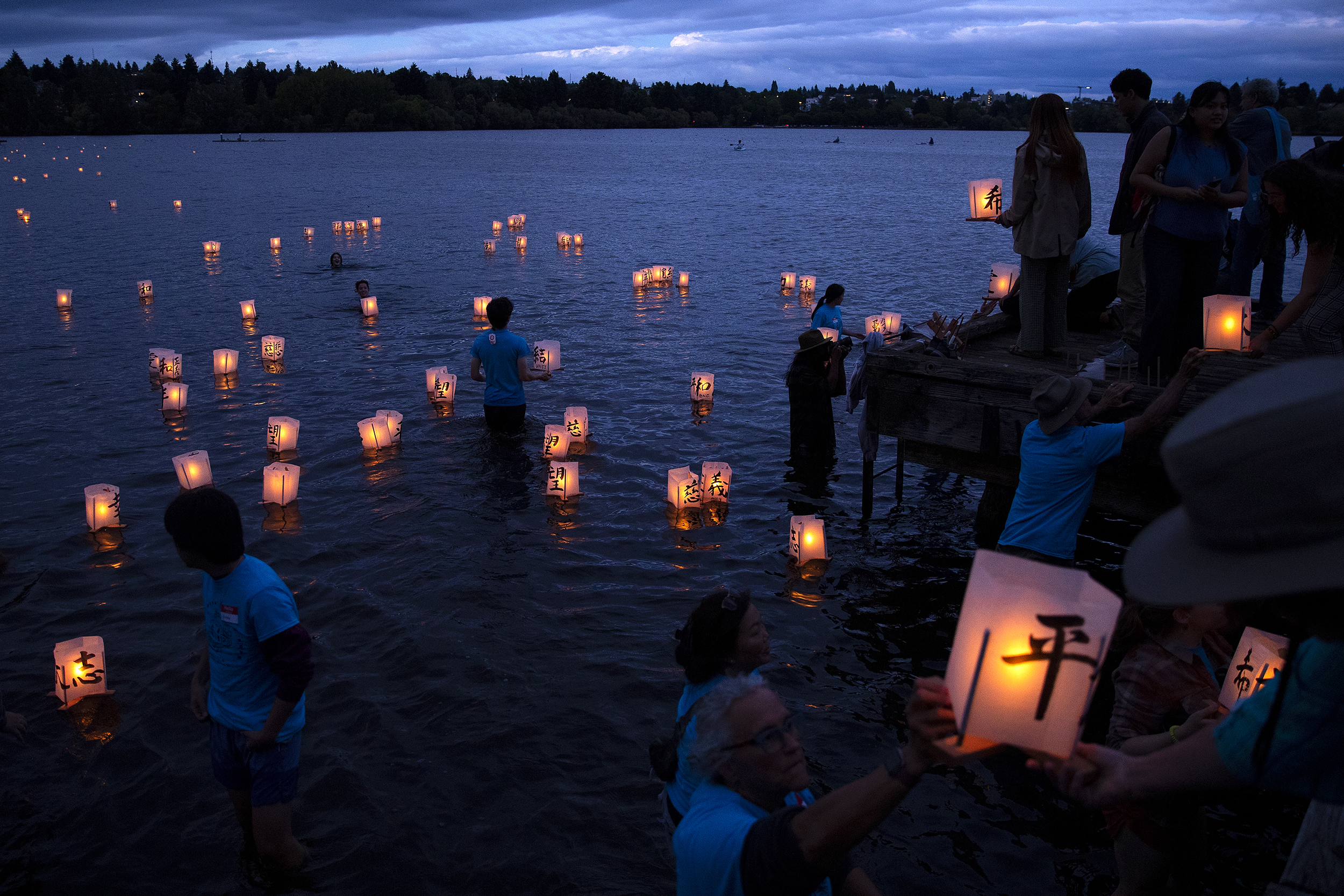 caption: Volunteers guide paper lanterns away from the shore as hundreds mark the 80th anniversary of the atomic bombings of Hiroshima and Nagasaki, on Wednesday, August 6, 2025, during Hiroshima to Hope at Green Lake in Seattle. The glowing memorial of lit paper lanterns with Japanese calligraphy and words of peace, love and justice, represented the thousands of lives lost, hope for a more peaceful future, and a visual reminder of a painful history. 