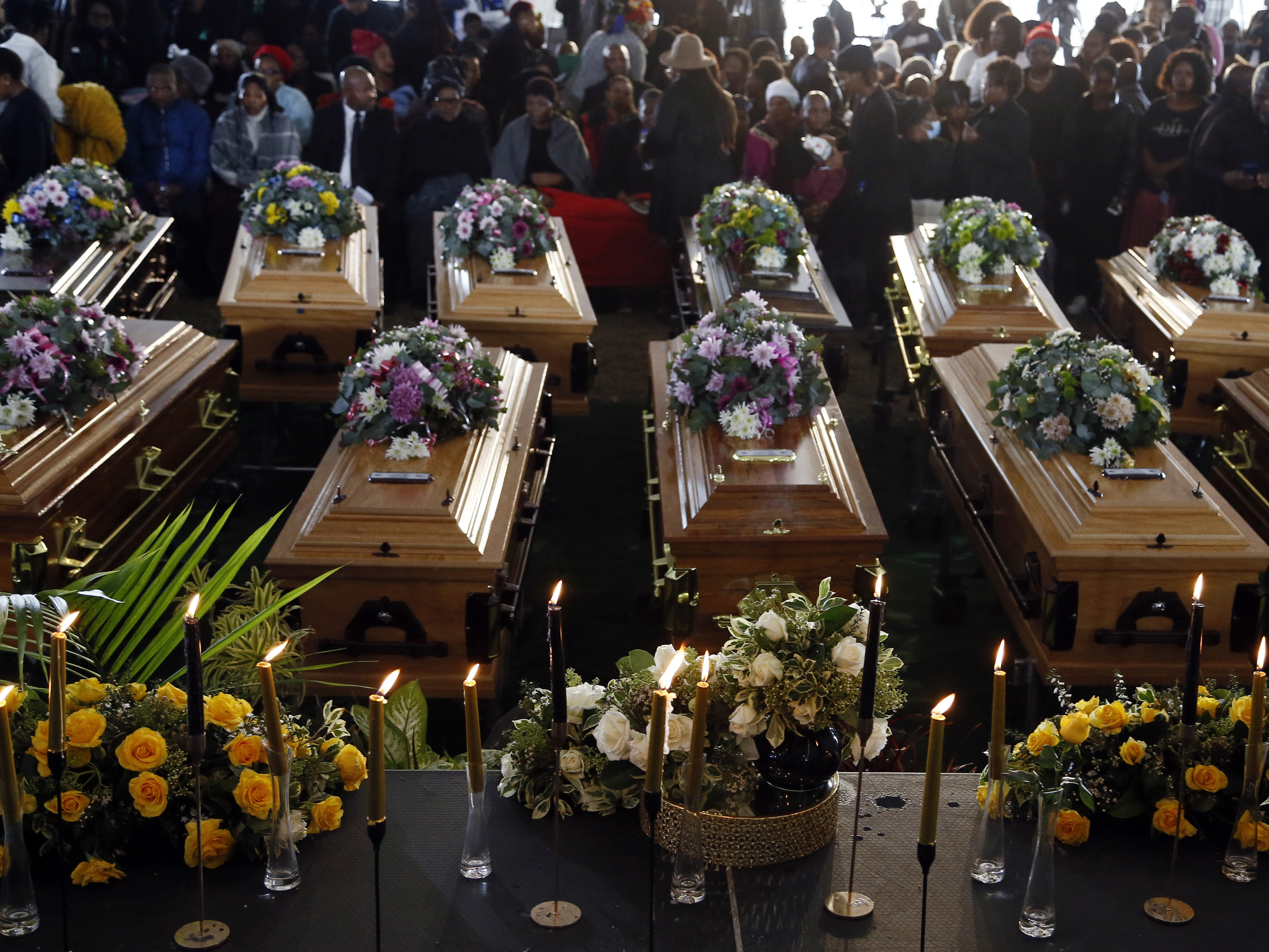 caption: Coffins of 21 teenagers who died in a mysterious tragedy at a nightclub in the early hours of June 26 are lined up during their funeral held in Scenery Park, East London, South Africa, on July 6. The toxic chemical methanol has been identified as a possible cause of the deaths.