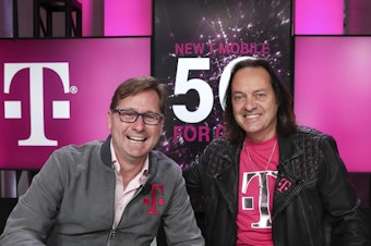 caption: T-Mobile's current CEO Mike Sievert and former CEO John Legere after closing a 2019 merger with Sprint. 