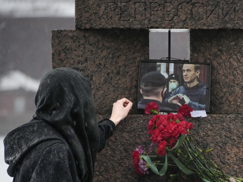 caption: A woman touches a photo of Alexei Navalny after laying flowers at the Memorial to Victims of Political Repression in St. Petersburg, Russia, on Saturday.