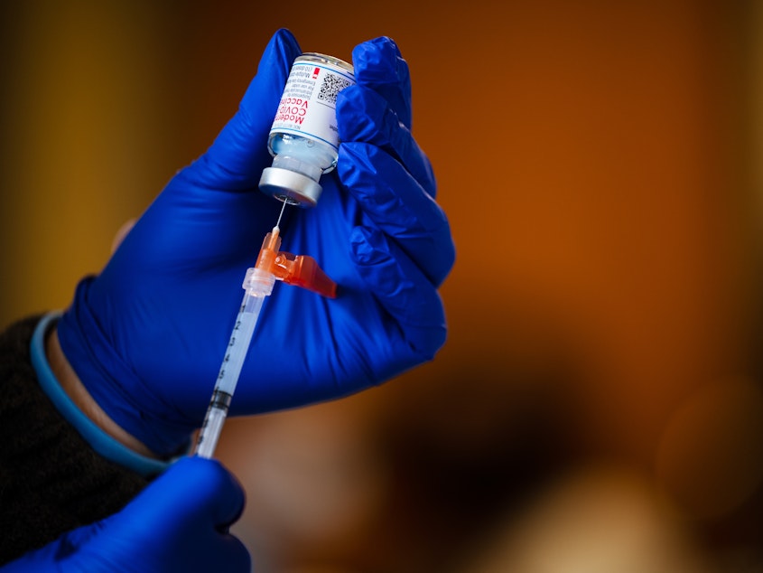 caption: A technician fills a syringe from a vial of the Moderna COVID-19 vaccine earlier this year.