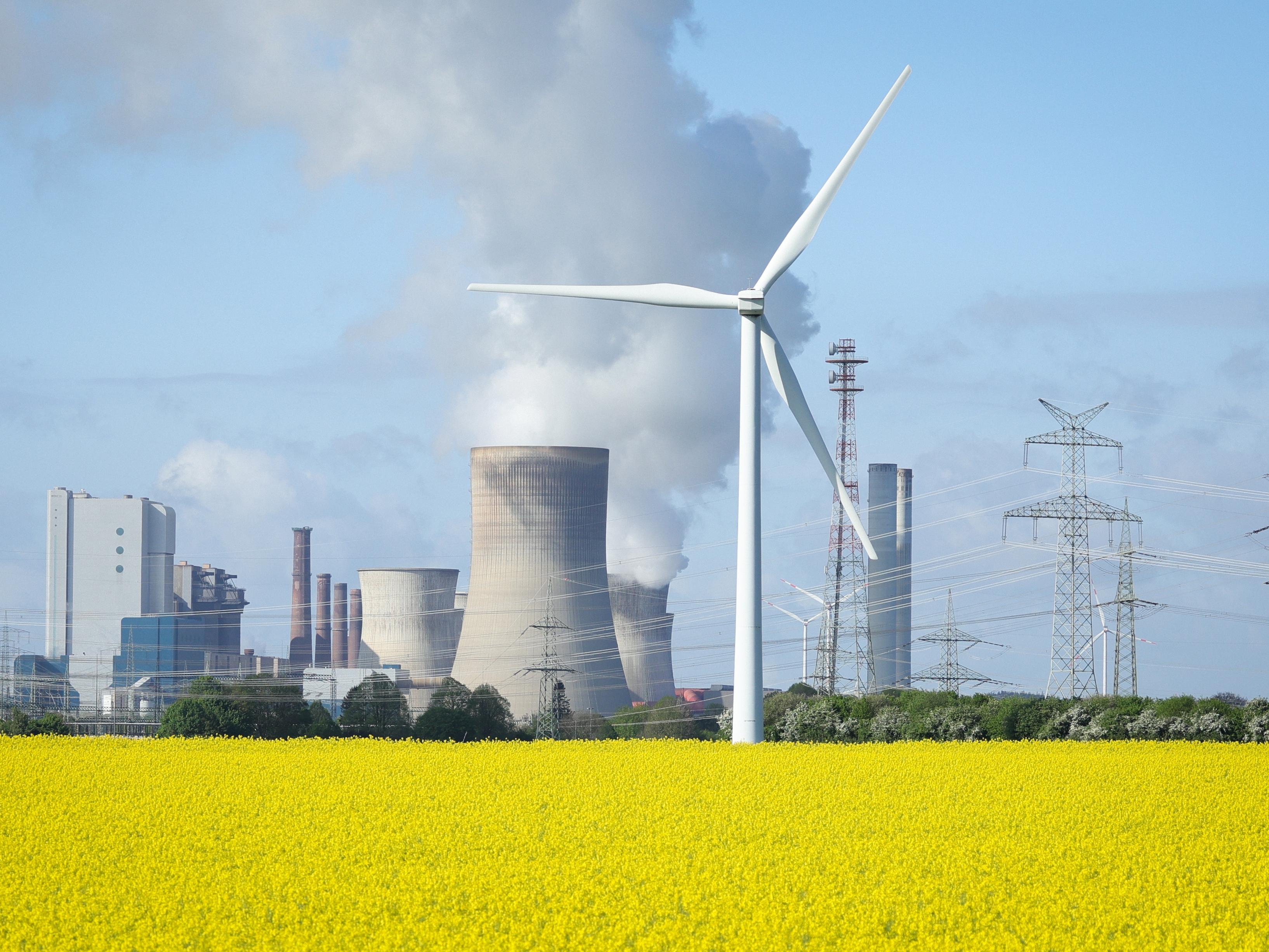caption: Wind turbines stand next to the Neurath coal-fired power plant on April 15, 2024, in Ingendorf, Germany.