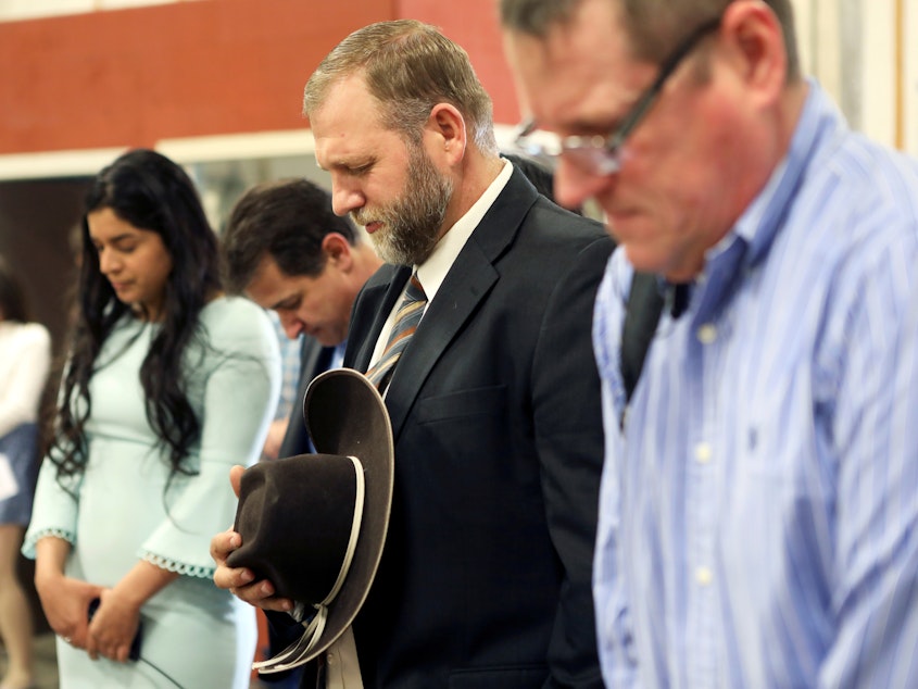 caption: Libertarian activist Ammon Bundy (second from right) prays during an Easter Sunday church service he organized despite concerns over the coronavirus outbreak in Emmett, Idaho.