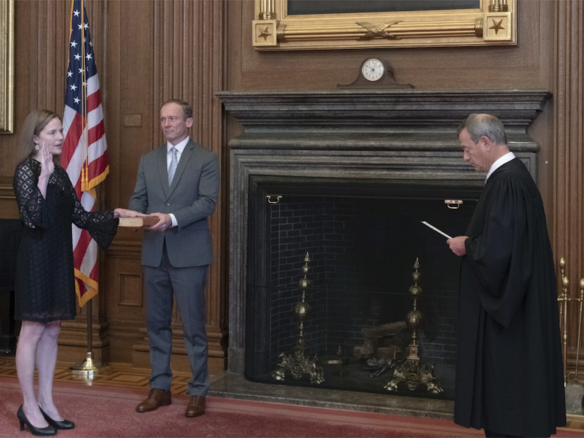 caption: Chief Justice John G. Roberts, Jr., administers the judicial oath to Judge Amy Coney Barrett at the Supreme Court on Tuesday. Barrett's husband, Jesse, holds the Bible.
