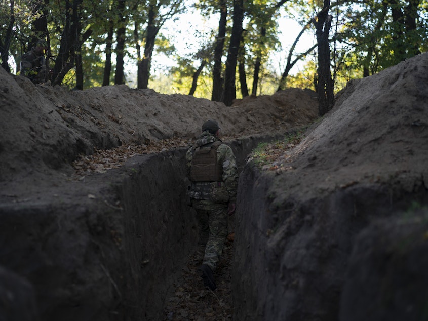 caption: A Ukrainian serviceman checks the trenches dug by Russian soldiers in a retaken area in the Kherson region, Ukraine, on Oct. 12, 2022.