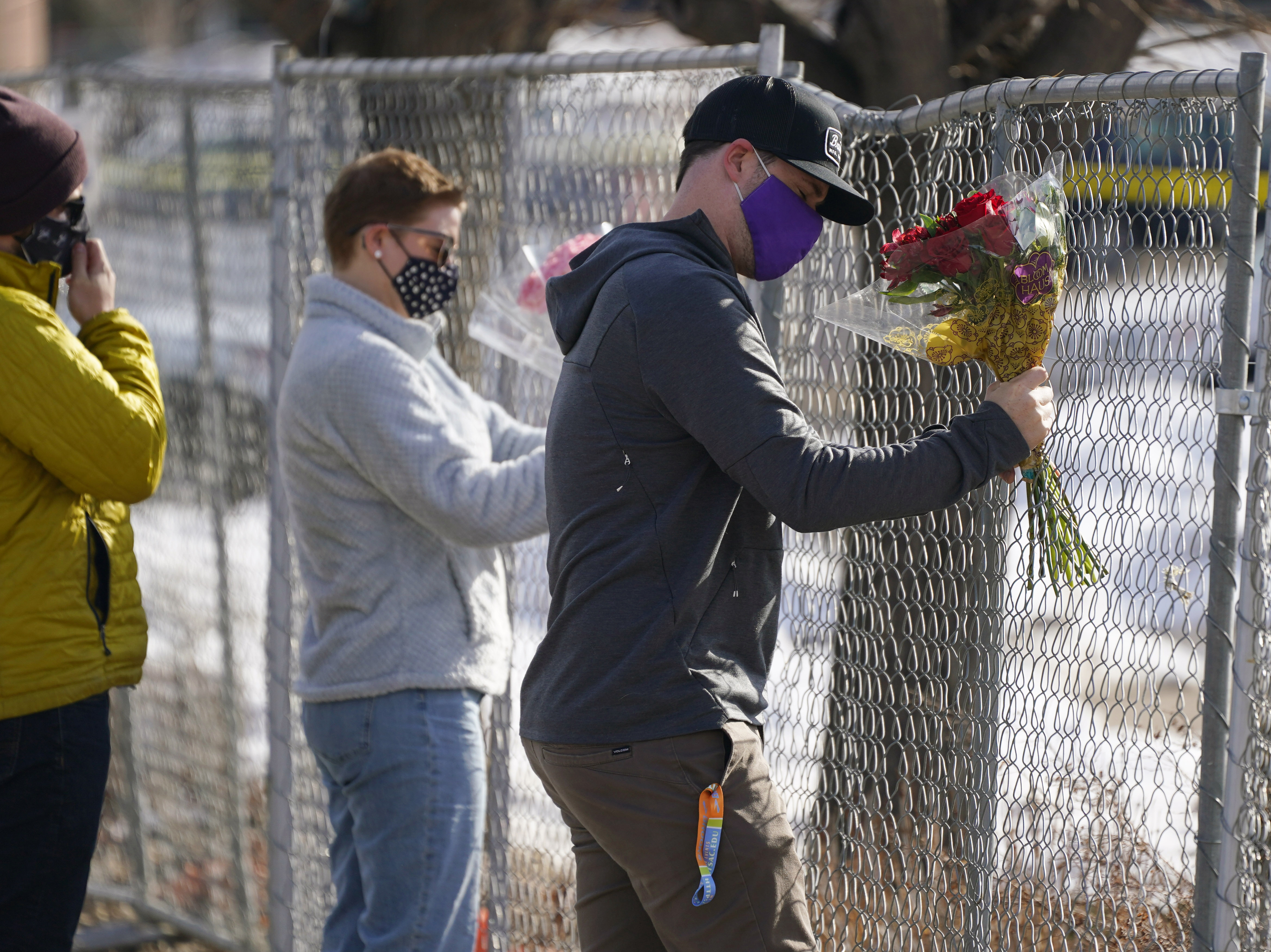 caption: Kiefer Johnson places flowers Tuesday in a makeshift fence around the parking lot outside the King Soopers grocery store in Boulder, Colo., where 10 people were killed a day earlier.