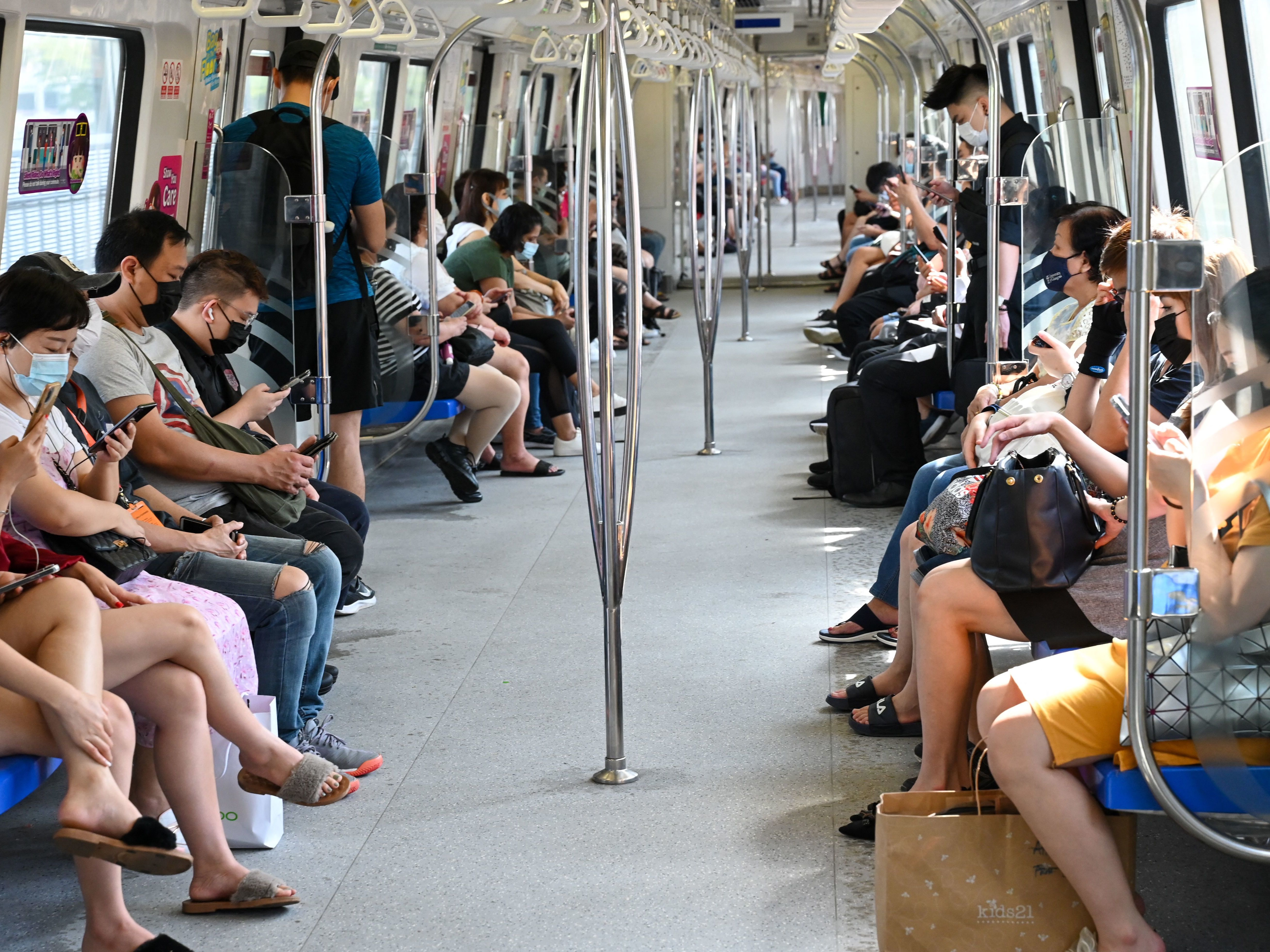 caption: People in Singapore mask up to take a mass rapid transit train on Friday. Singapore has one of the highest vaccination rates in the world. As of Sunday, 85% of its population was fully vaccinated.