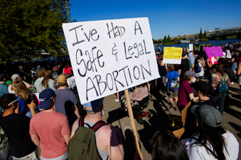 caption: Protesters hold signs demonstrating against the Supreme Court's decision to overturn Roe v. Wade in Portland, Ore., Friday, June 24, 2022. The Supreme Court has ended constitutional protections for abortion that had been in place nearly 50 years, a decision by its conservative majority to overturn the court's landmark abortion cases. 