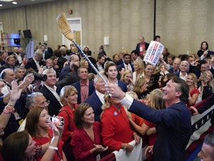 caption: Glenn Youngkin, governor-elect of Virginia, holds a broom while greeting attendees after speaking during an election night event in Chantilly, Va. Youngkin defeated Democrat Terry McAuliffe in Virginia's closely watched governor's race.
