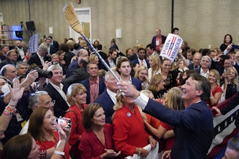 caption: Glenn Youngkin, governor-elect of Virginia, holds a broom while greeting attendees after speaking during an election night event in Chantilly, Va. Youngkin defeated Democrat Terry McAuliffe in Virginia's closely watched governor's race.