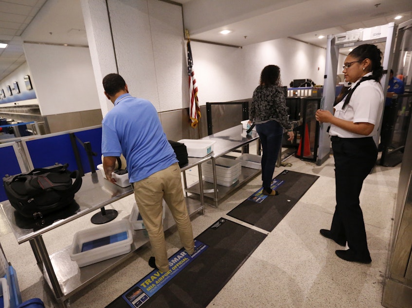 caption: A Transportation Security Administration officer watches as travelers put their items through an X-ray machine in 2017 at Miami International Airport. The TSA says it's finding significantly more firearms in carry-on luggage despite a huge drop in air travel.