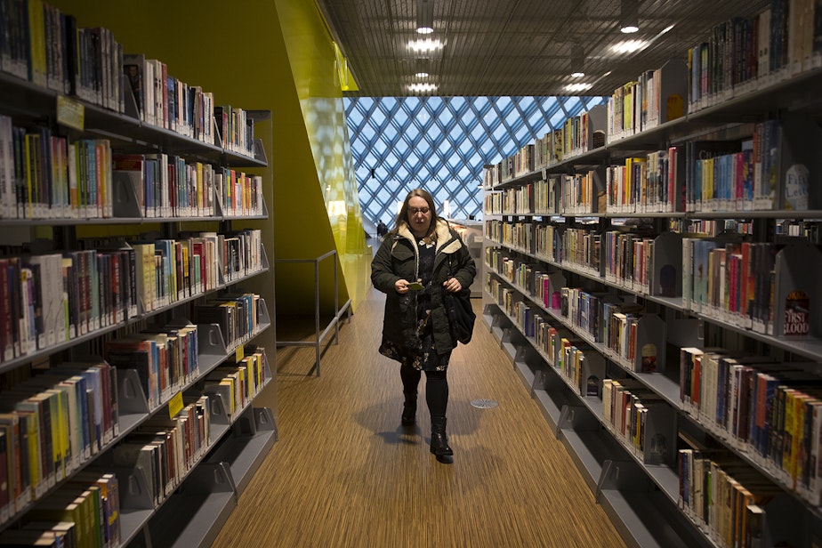 caption: Kara Peters walks through the Seattle Public Central Library to her desk before starting her shift on Wednesday, January 22, 2020, in Seattle.