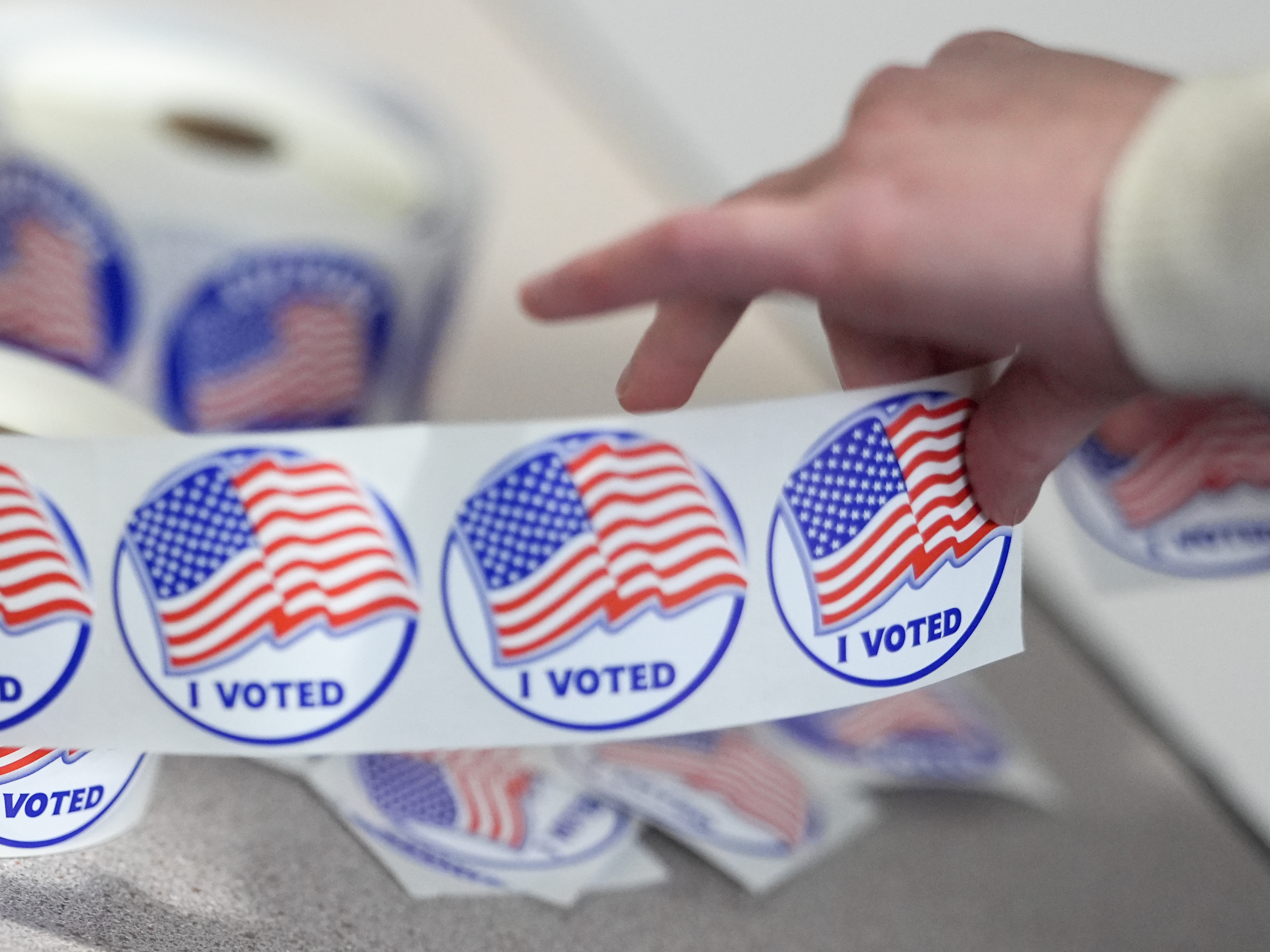 caption: An election worker tears off "I Voted" stickers during the Virginia redistricting referendum at Fairfax Government Center on Tuesday in Fairfax, Va.