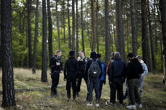caption: A Federal Police officer speaks into his radio as he and a colleague track down a group of migrants who illegally crossed the border from Poland into Germany, southeast of Berlin, Oct. 11. On Wednesday, European Union leaders hailed a major breakthrough in talks on new rules to control migration.
