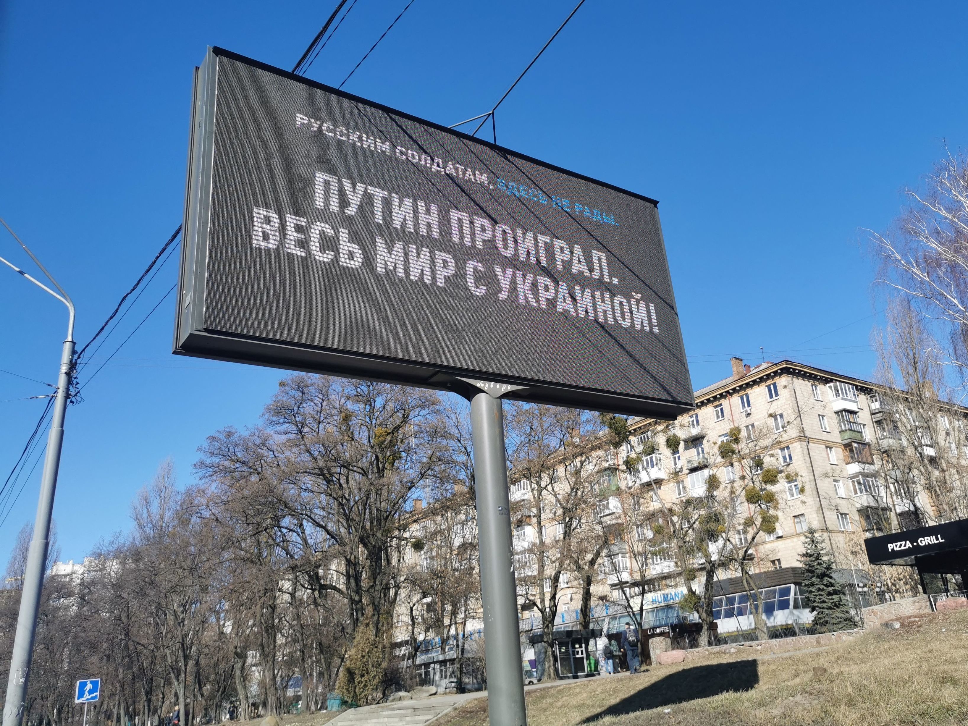 caption: An electronic billboard along Kyiv's Victory Avenue, the route Russian tanks are expected to take, shows a message to Russian soldiers reading "Putin lost, the entire world is with Ukraine," on  Monday.