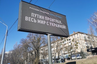 caption: An electronic billboard along Kyiv's Victory Avenue, the route Russian tanks are expected to take, shows a message to Russian soldiers reading "Putin lost, the entire world is with Ukraine," on  Monday.