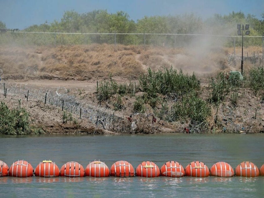 caption: A barrier to deter migrants from crossing from Mexico into the U.S. floats in the Rio Grande at Eagle Pass, Texas.