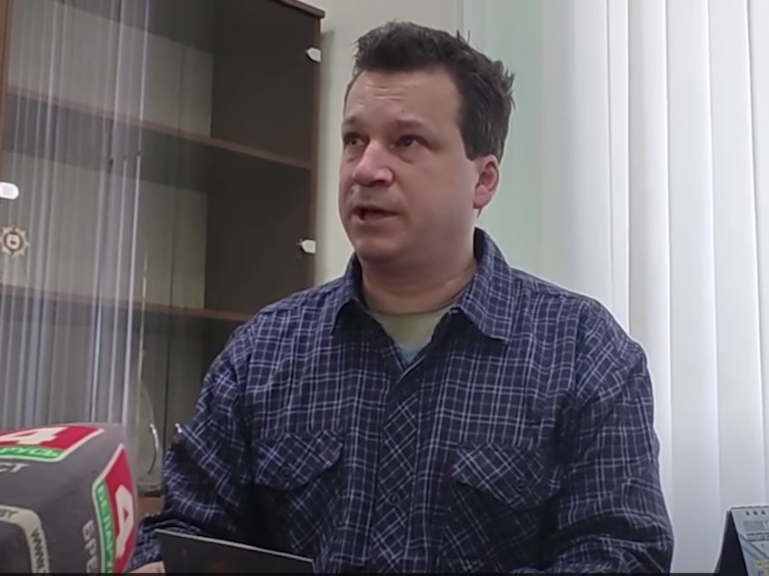 caption: Evan Neumann, who is wanted by the FBI, holds his new Belarusian documents at the department of citizenship and migration office in Brest, Belarus.