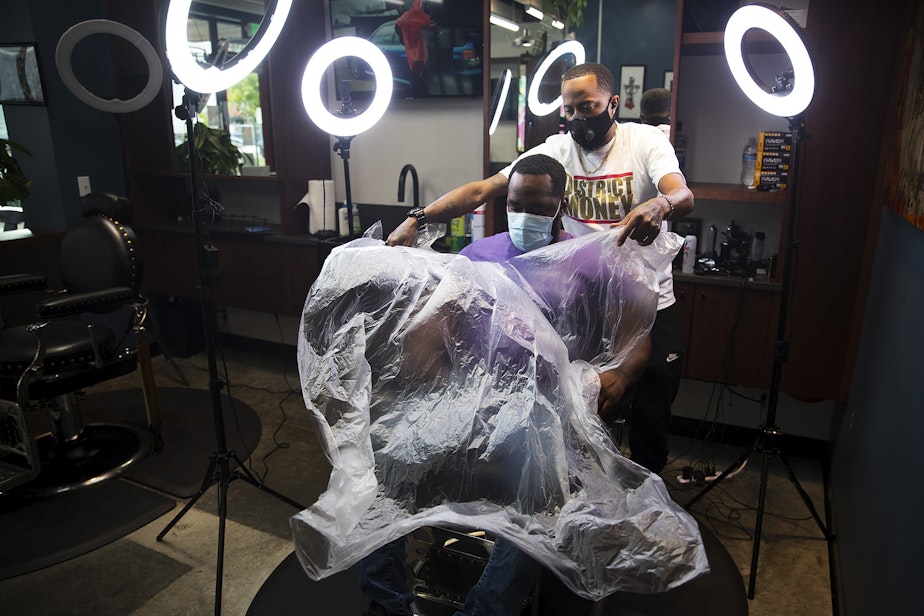 caption: Barber Jasen Moore gets ready to cut Terrence Brown's hair at Earl's Cuts and Styles Barbershop on October, 15, 2020, in Seattle. “At first it was a lot of anxiety,” said Moore, who has been a barber for six years. “There’s a little fear of the unknown. I think that moving forward, the Covid pandemic has allowed us to step back and really see how we can get better as a business for the community to make everybody feel safe and comfortable while they’re at Earl’s Cuts and Styles."