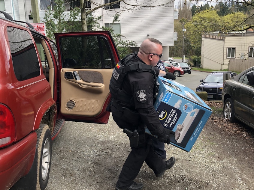 caption: SPD Officer Aaron Johnson removes stolen merchandise from a vehicle in Lake City. SPD said it would be returned to the Lowe's in Rainier Valley.