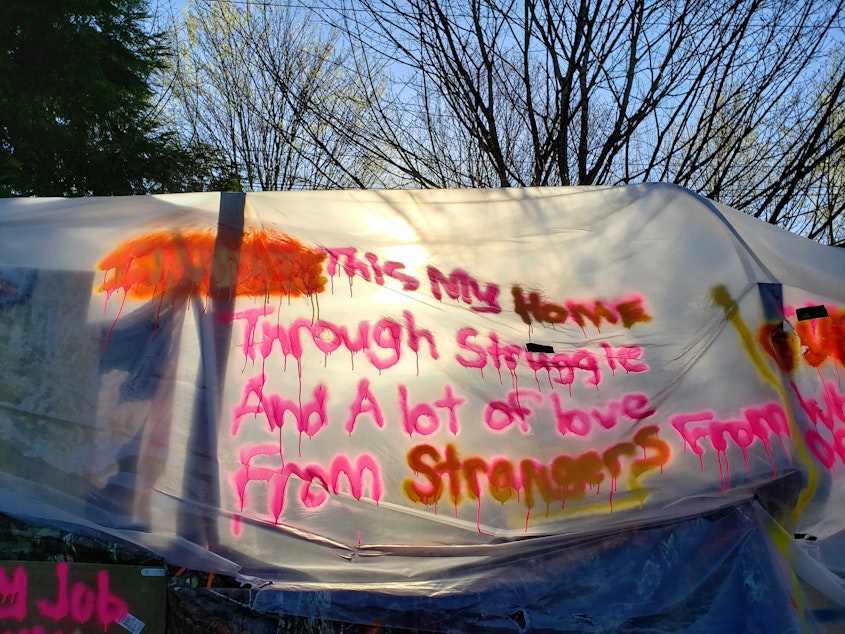 caption: A spray painted message on this tent reads, "This is my home through struggle and a lot of love from strangers" on the morning of the camp clearing.
