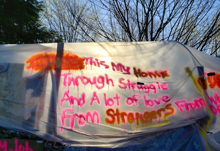 caption: A spray painted message on this tent reads, "This is my home through struggle and a lot of love from strangers" on the morning of the camp clearing.