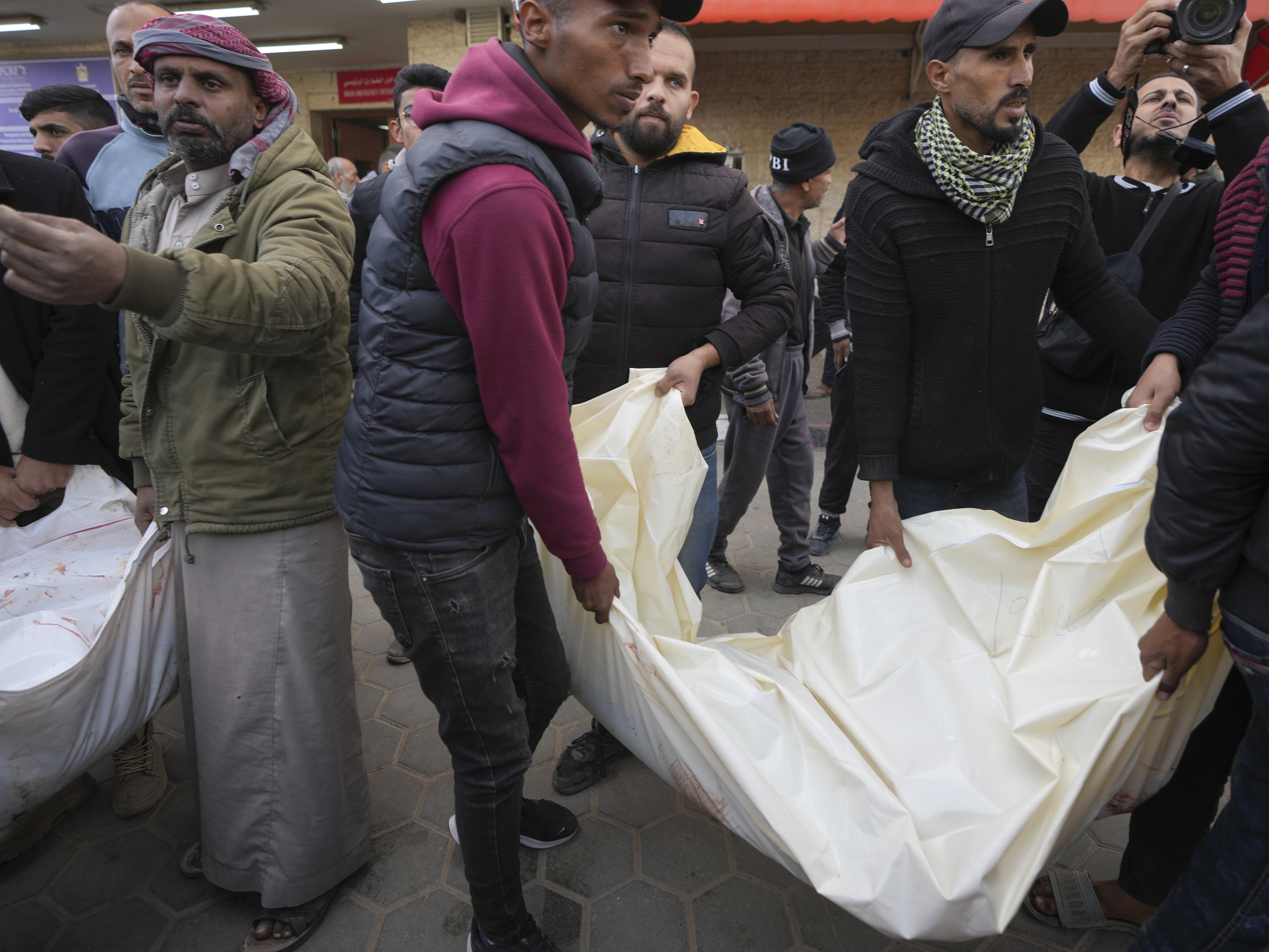 caption: Palestinians carry white sacks containing the bodies of those killed in overnight Israeli airstrikes on the Maghazi refugee camp, at Al-Aqsa Hospital, in Deir al-Balah, central Gaza Strip, on Saturday.