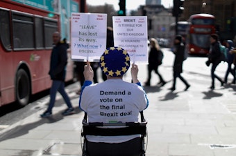 caption: An anti-Brexit activist demonstrates outside of the Houses of Parliament in London on Thursday, before a vote on whether to postpone Britain's exit from the European Union.