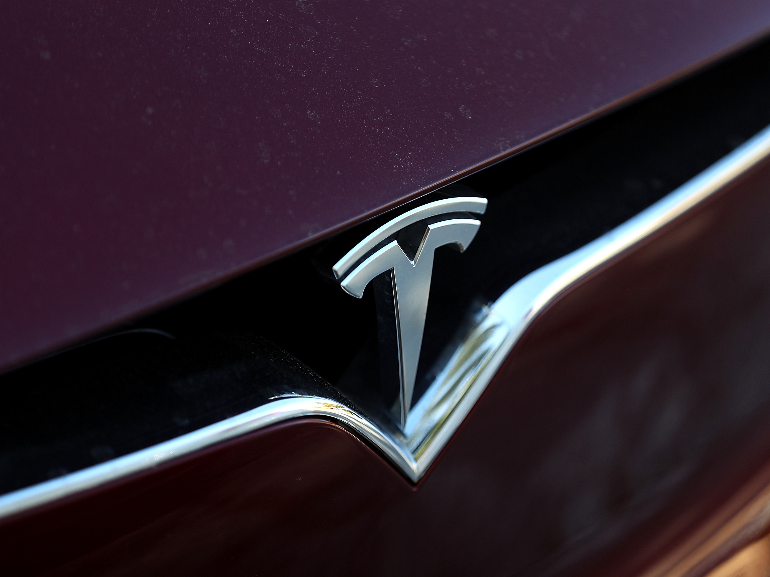 caption: The Tesla logo is displayed on the front of a Tesla Model X in Los Angeles in 2017.