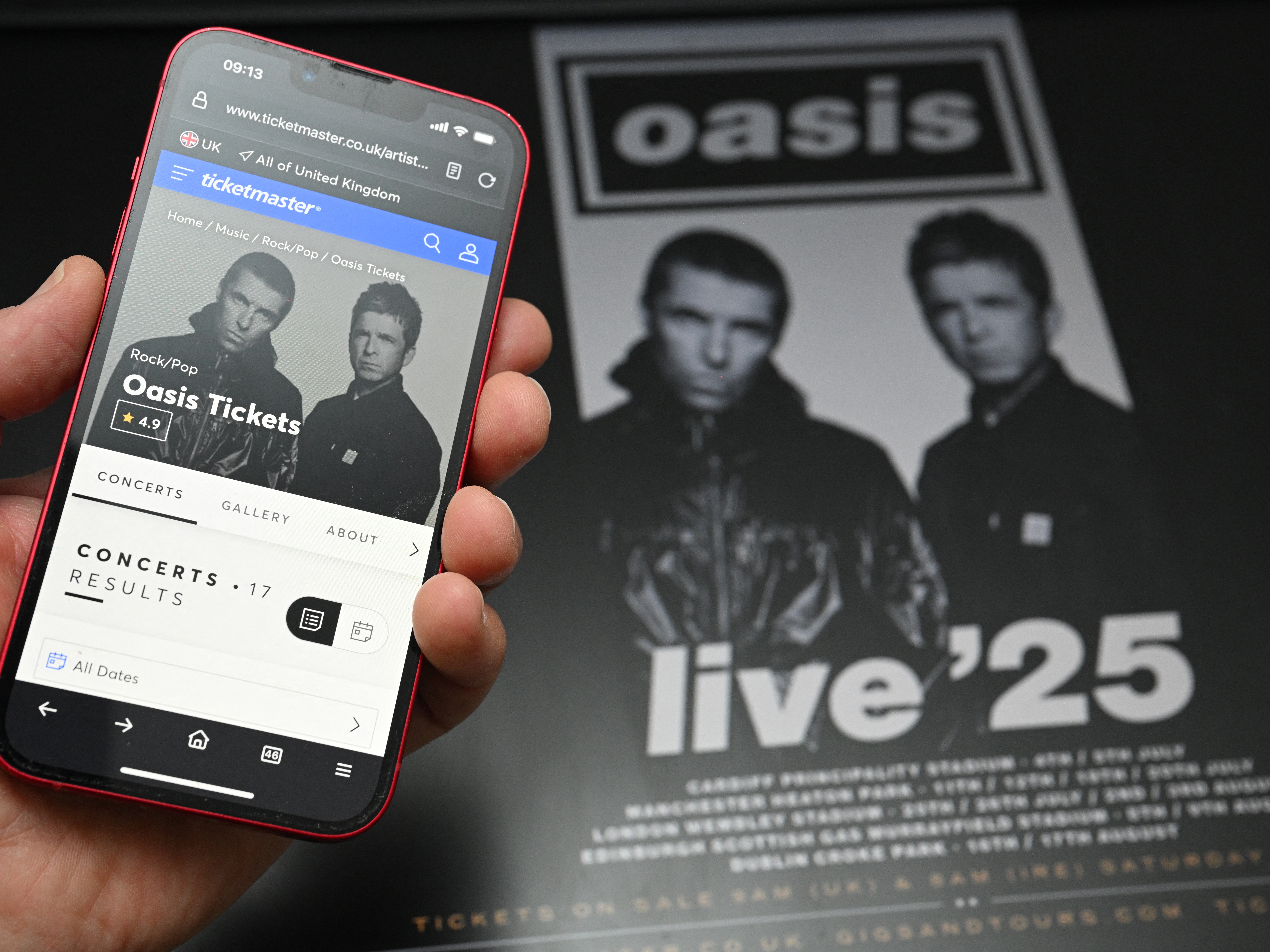 caption: A fan uses a smartphone to access an online ticket sales website to purchase tickets for Oasis' "Live '25" tour. Oasis fans queued online early Saturday to buy tickets for the eagerly awaited reunion tour, but many tickets had already been scooped up by resellers charging many times over original ticket prices.