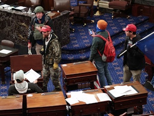 caption: Larry Rendall Brock Jr., an Air Force veteran, is seen inside the Senate Chamber wearing a military-style helmet and tactical vest during the rioting at the U.S. Capitol. Federal prosecutors have alleged that before the attack, Brock posted on Facebook about an impending "Second Civil War."