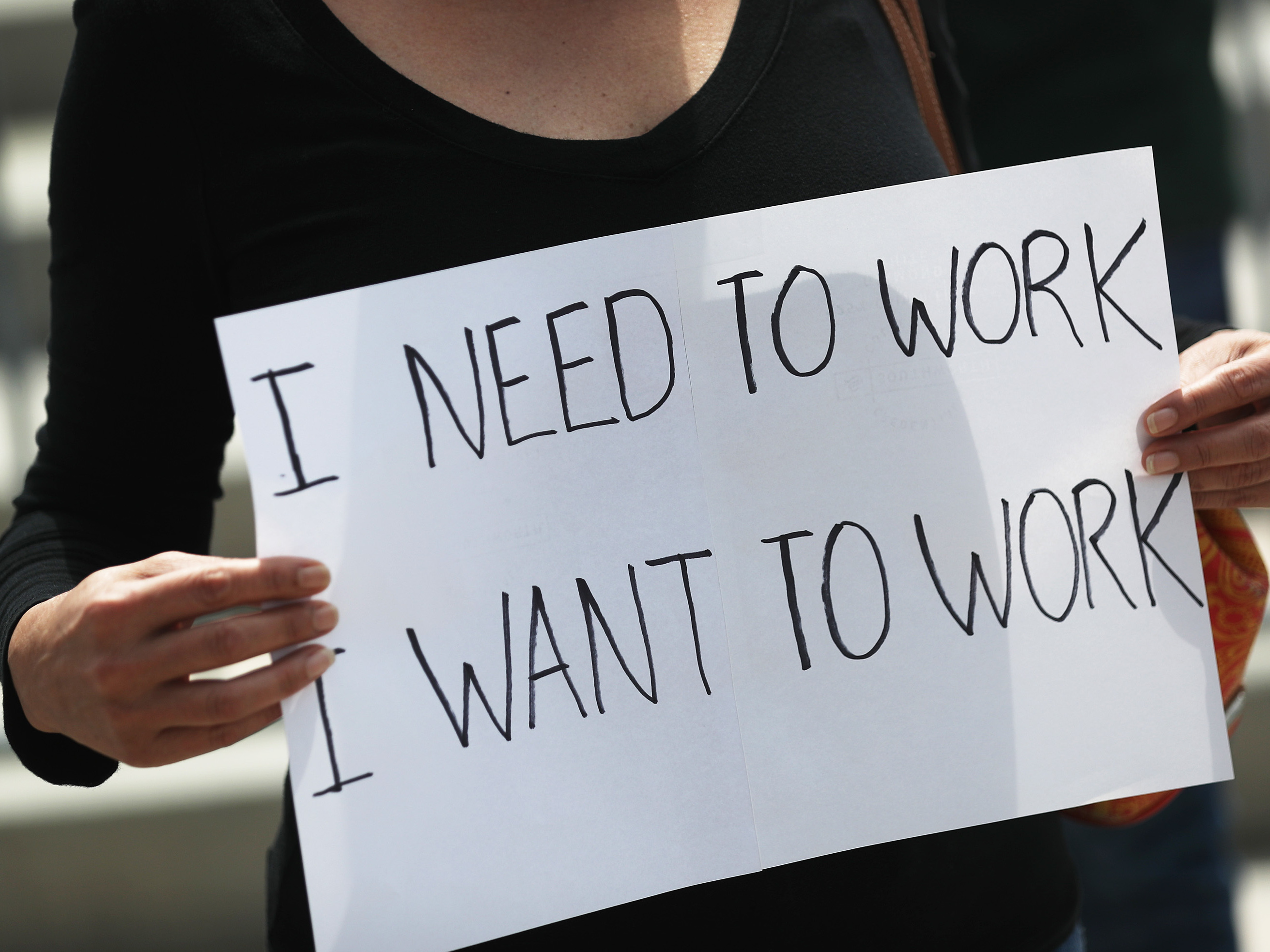 caption: A protester holds a sign as she joins with restaurant owners, workers and supporters on July 10, 2020, to protest measures in Miami to close indoor seating amid a rise in coronavirus cases. The number of unemployment claims rose for a second week, reinforcing concerns about the economy.