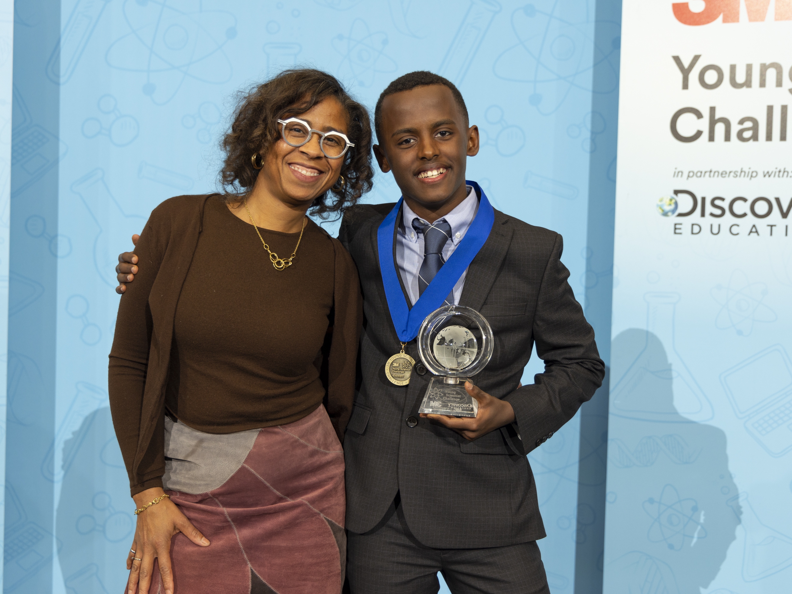 caption: Heman Bekele is <em>Time's</em> "2024 Kid of the Year," honored for his work on a cancer-fighting soap. Last year he won a $25,000 prize from 3M for his research. Above, he's pictured with 3M mentor, Deborah Isabelle, who's said of Bekele, "he's going to continue to inspire other young people to realize that science can make a positive difference."<br>