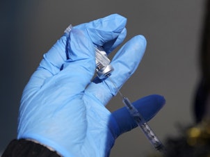 caption: A nurse fills a syringe with COVID-19 vaccine at a mass vaccination site in Kansas City, Mo. on March 19, 2021.