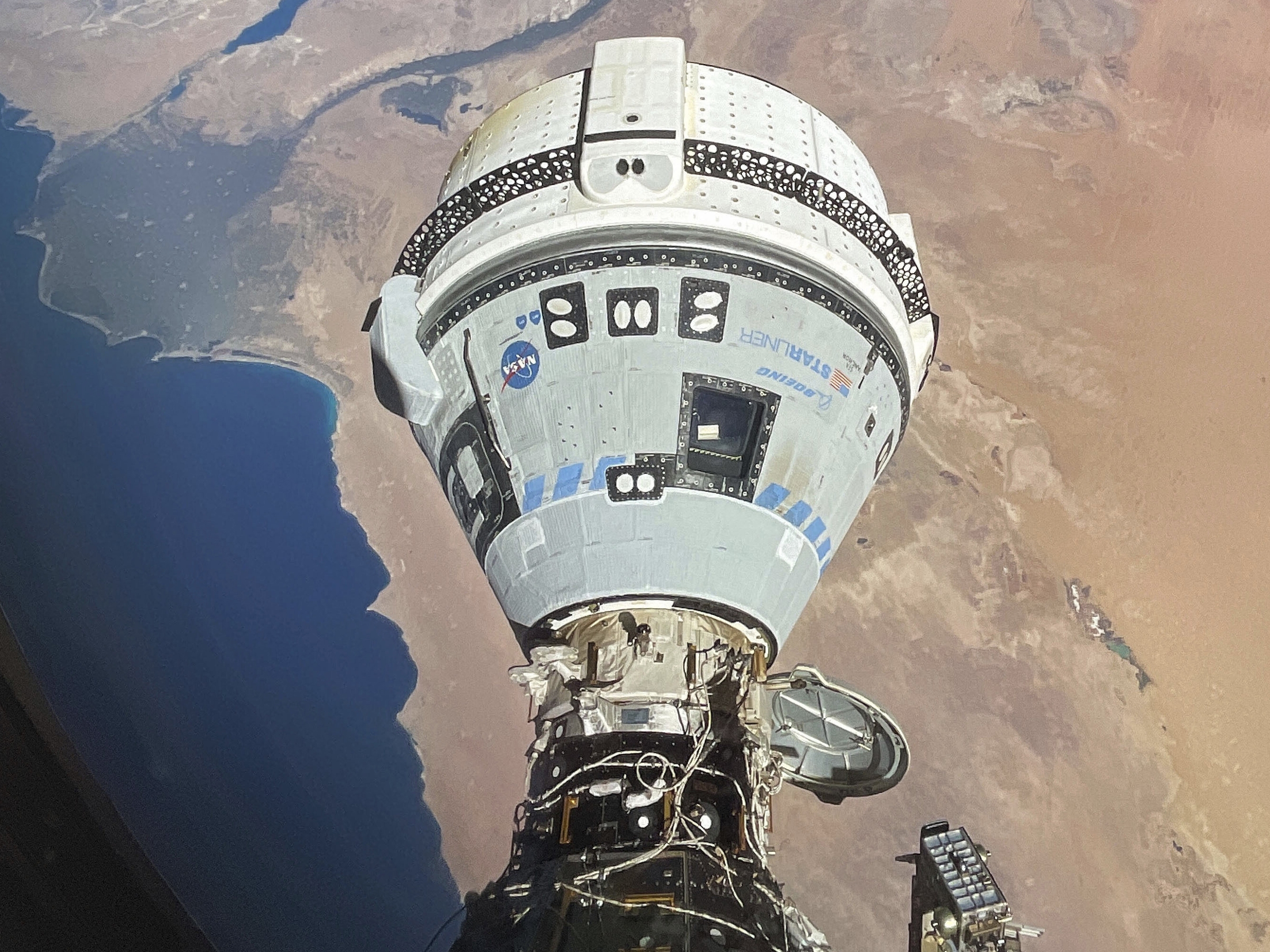 caption: The Starliner spacecraft docked with the International Space Station and orbiting 262 miles above Egypt's Mediterranean coast on June 13. NASA says additional testing is needed before Starliner can return to Earth.