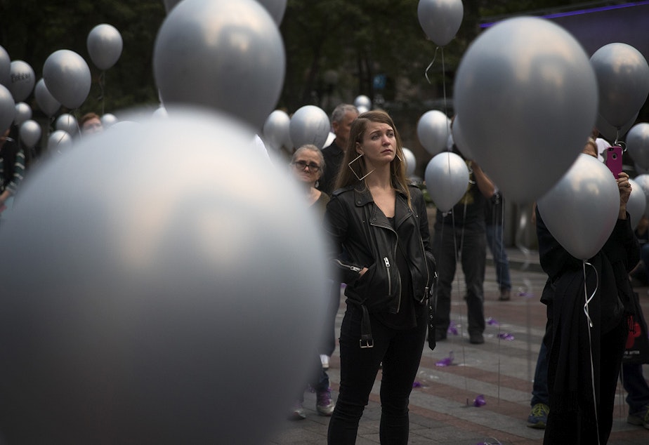 caption: Cassandra Piester, center, listens to speakers during an event honoring the 379 lives lost in King County during 2017 to overdose, on Thursday, August 30, 2018, at Westlake Park in Seattle. Piester's cousin Amber Roberts died of an overdose in 2015. 