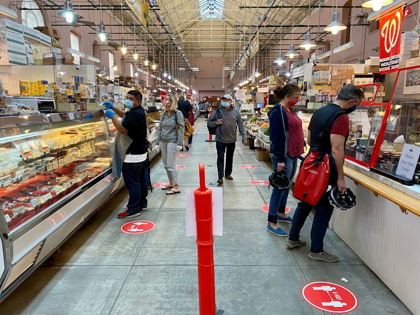 caption: Shoppers wear masks at Eastern Market in Washington, D.C., on May 17. An NPR/<em>PBS NewsHour/</em>Marist poll finds that most Americans think it will take at least six months to return to normal daily life.