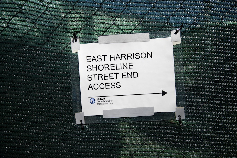 caption: A sign pointing toward Hidden Beach, the shoreline street end of E. Harrison St., is shown along a construction fence on a neighboring private property, on Monday, June 24, 2024, along the shore of Lake Washington in Seattle.