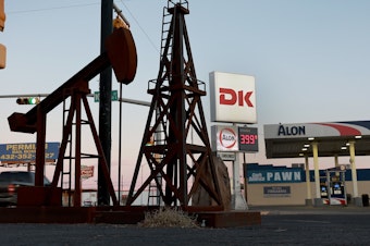 caption: A statue of a pumpjack and drilling rig sits next to a gas station in Odessa, Texas, on March 13. U.S. oil companies are under pressure to drill more, but they are constrained in how much they can do.