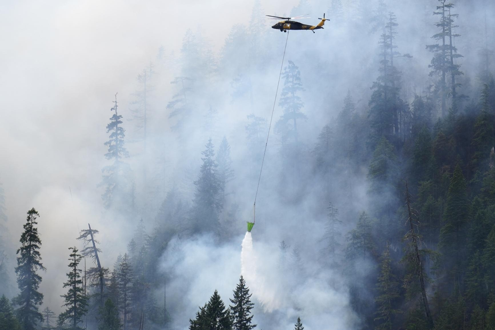 caption: A helicopter drops water on the Bear Gulch Fire on Washington's Olympic Peninsula on Aug. 5, 2025.