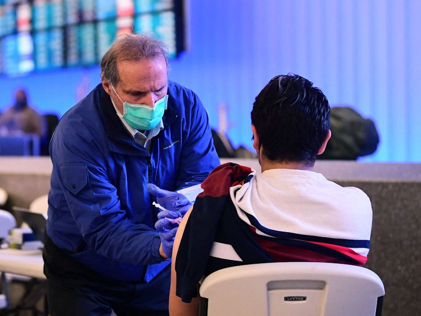 caption: A pop-up clinic inside Los Angeles International Airport offered free vaccinations and boosters for holiday travelers last December. A new round of vaccinations may be needed before next winter.