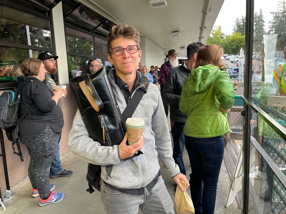 caption: Drummer Angie Tabor prepares to walk on the ferry at Bainbridge Island on Sept. 7, 2023. For rehearsals in Seattle, Tabor would normally drive on the ferry with a drum set. But today, they have arranged to borrow a set, and are only carrying on a set of sticks.