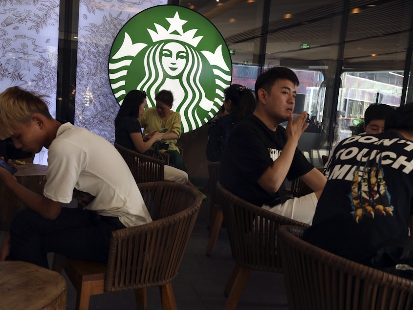 caption: In a photo taken in May, customers enjoy their drinks at a Starbucks in Beijing. The U.S.-based coffee chain as decided to close more than half its stores in mainland China due to the coronavirus outbreak.
