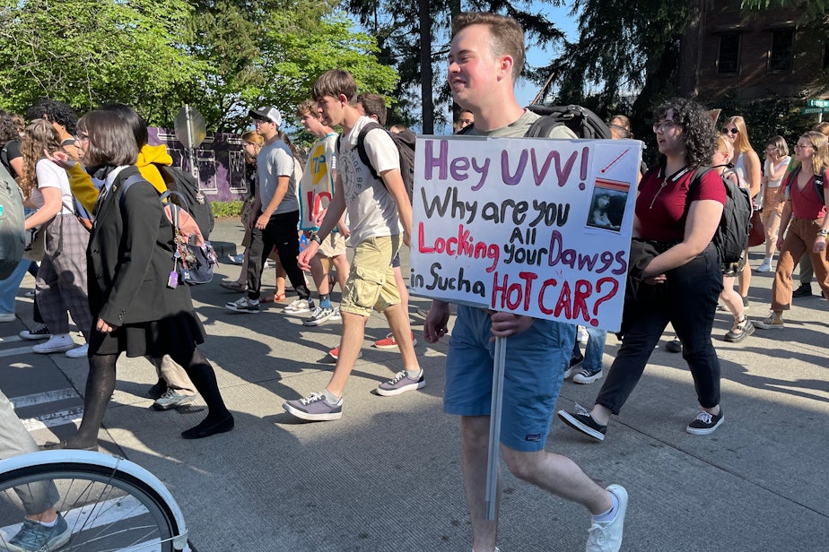 caption: UW senior Nicholas Birkhead of Shoreline, holding sign, studies finance and supply chains and is looking for a career in clean energy.