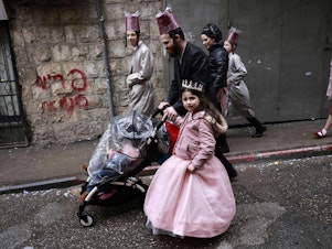 caption: Jewish men and children in Purim costumes celebrate in the Mea Shearim ultra-Orthodox neighbourhood in Jerusalem, on March 18, 2022. The Purim holiday is celebrated with parades and costume parties to commemorate the deliverance of the Jewish people from a plot to exterminate them in the ancient Persian empire 2,500 years ago, as recorded in the Biblical Book of Esther.