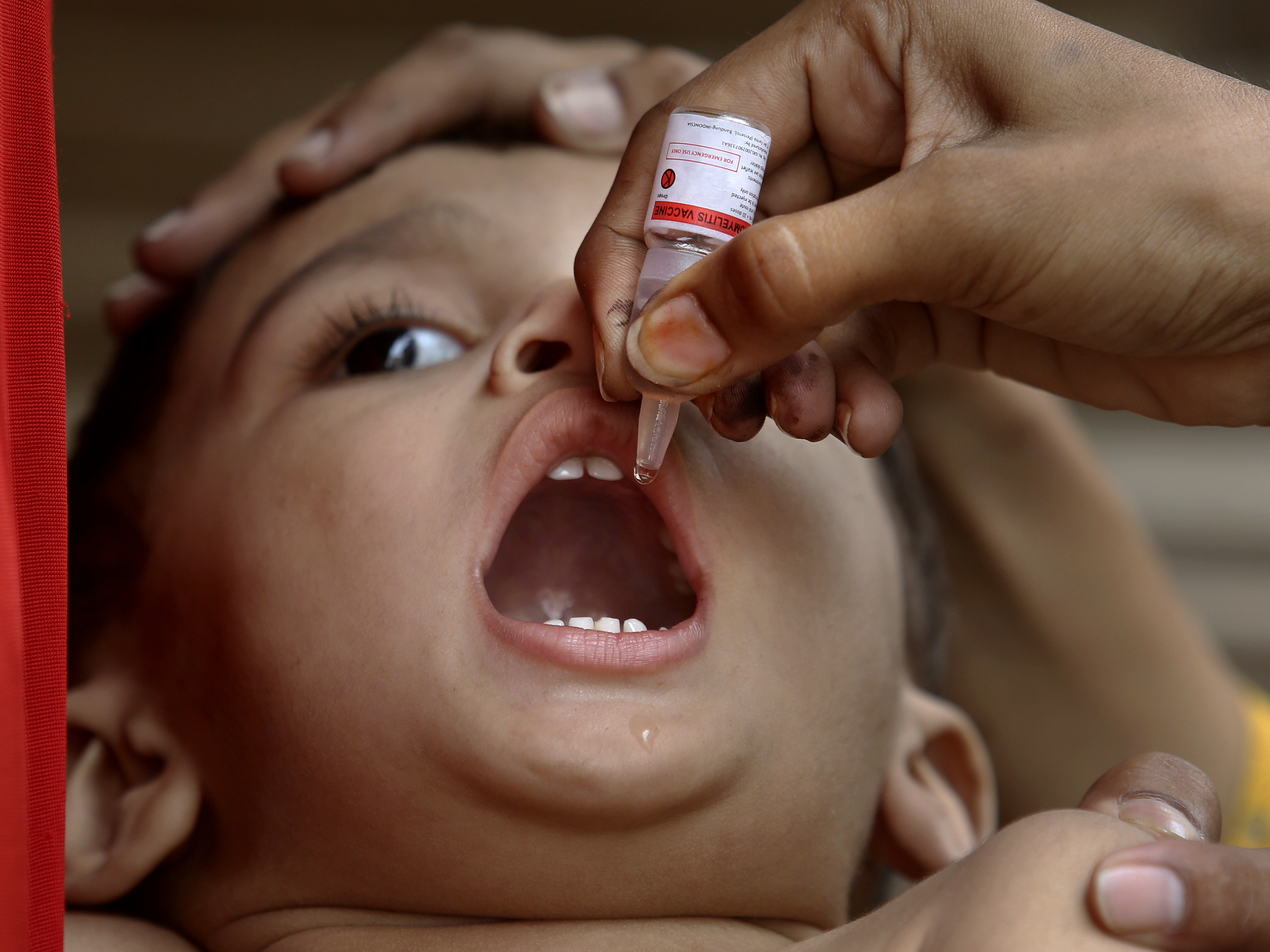 caption: A health worker administers a polio vaccine to a child in Karachi, Pakistan, on June 9.