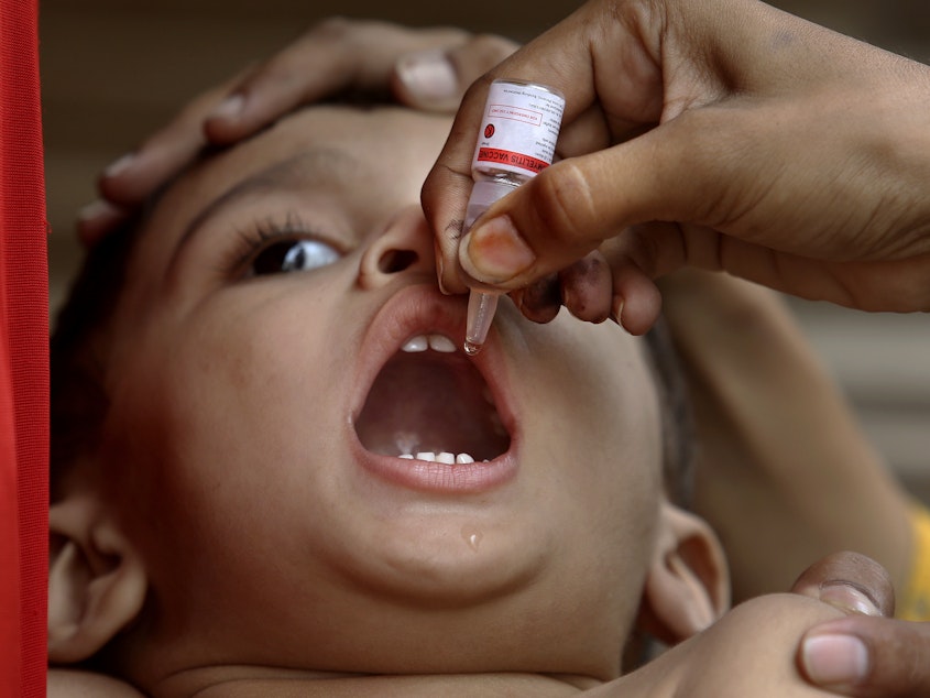 caption: A health worker administers a polio vaccine to a child in Karachi, Pakistan, on June 9.