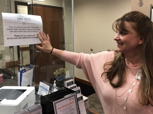 caption: Tove Skaftun, the chief nursing officer for the Community Health Center of Snohomish County, points out a sign warning people who could have been exposed to the new coronavirus from China to identify themselves.